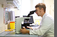 Mann schaut in Mikroskop im Institut für Mikrobiologie der Uniklinik Rostock